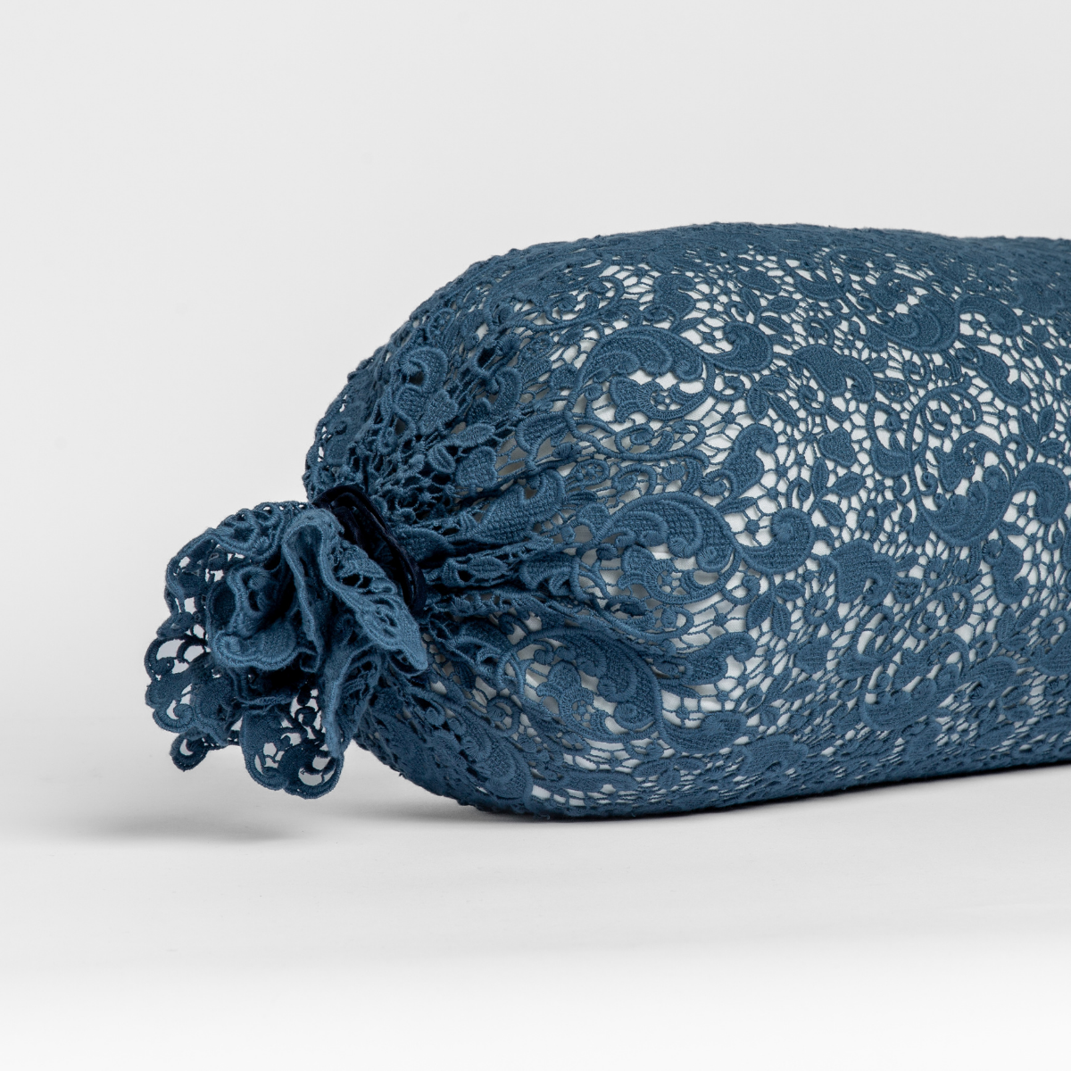 Midnight: one end of a lace boslter cover on a winter white liner against a white background.