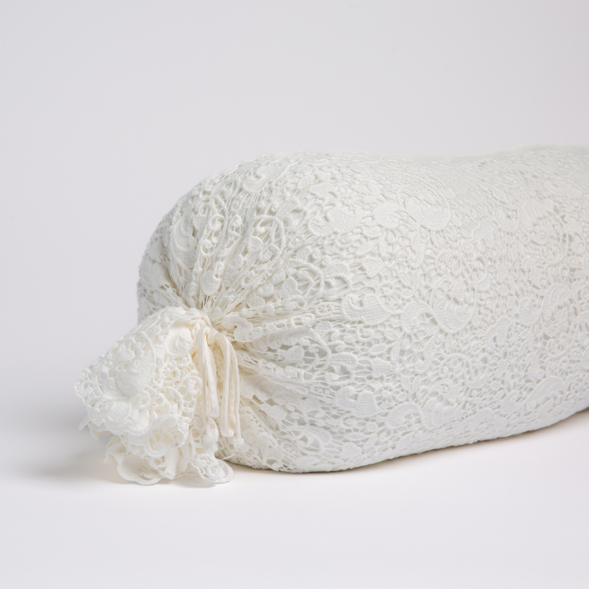Winter White: one end of a lace boslter cover on a winter white liner against a white background.