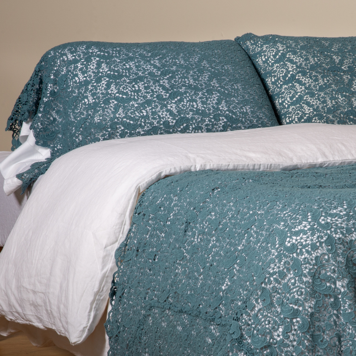 Cenote: a pair of cotton lace pillowcase covers on winter white liners shown on a bed dressed in winter white linen with a matching cotton lace bed scarf.