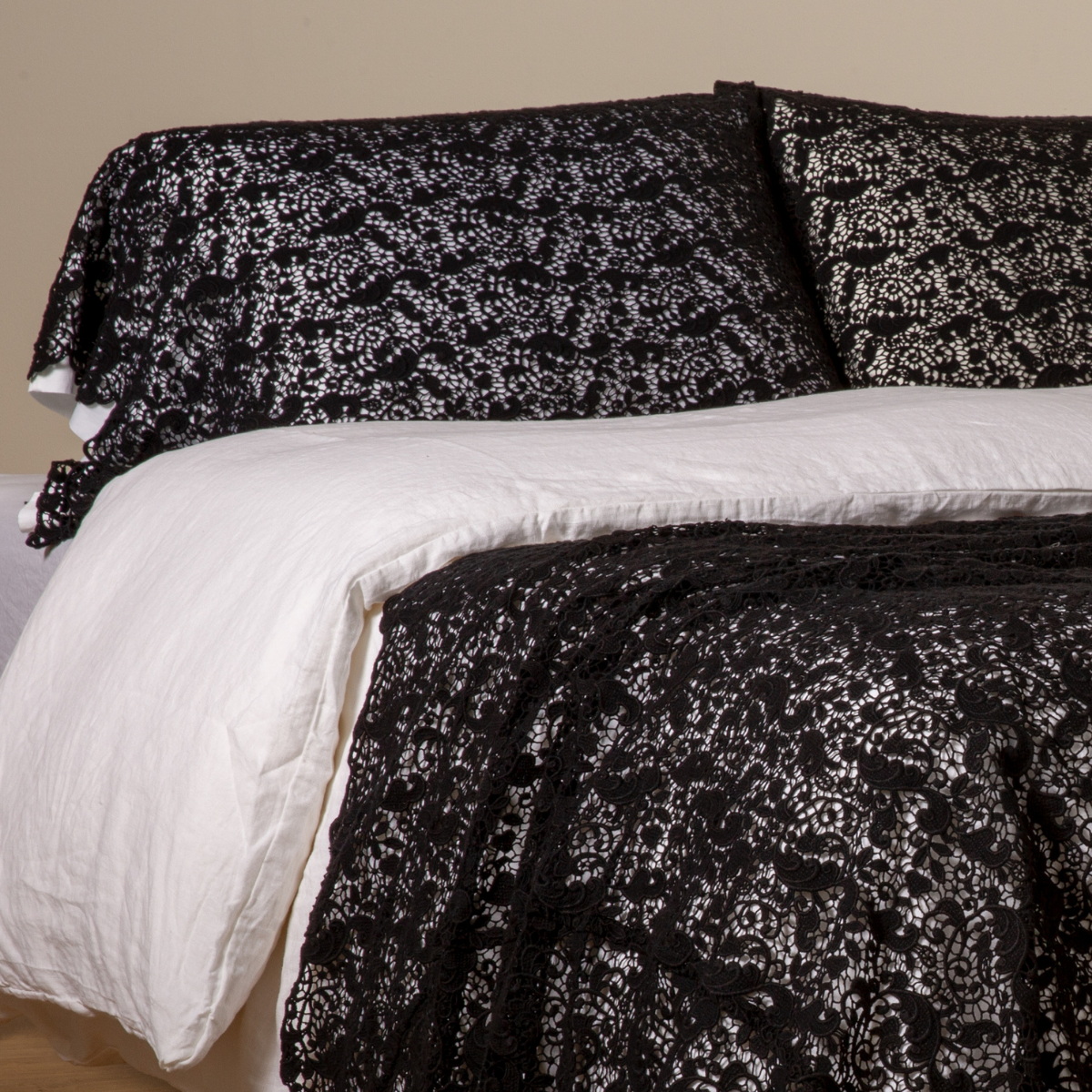 Corvino: a pair of cotton lace pillowcase covers on winter white liners shown on a bed dressed in winter white linen with a matching cotton lace bed scarf.