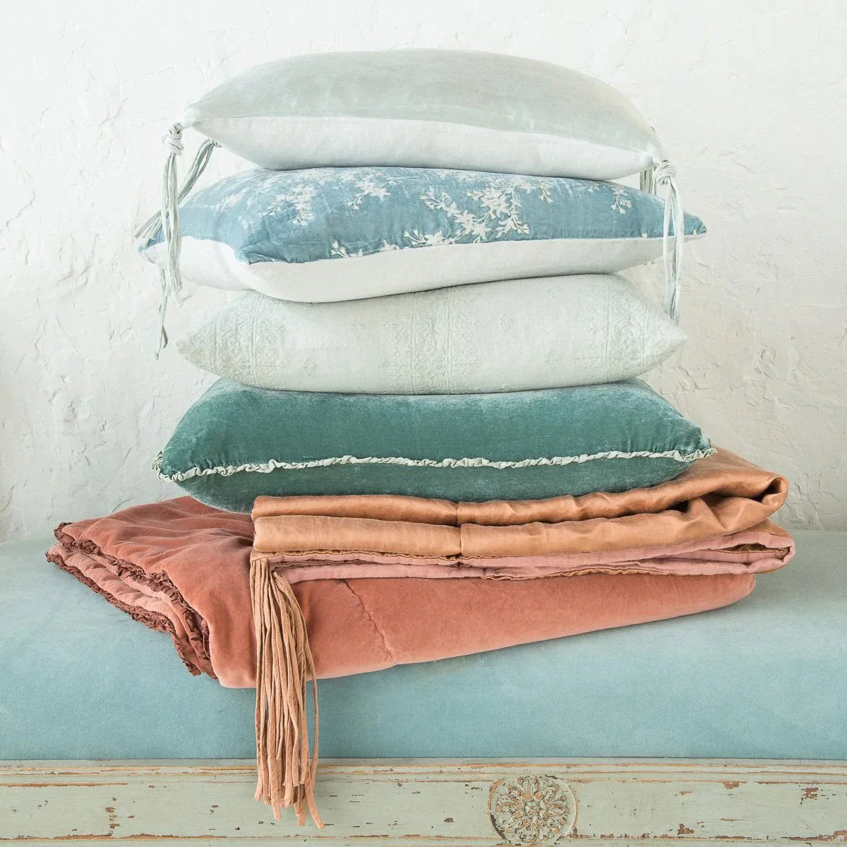 : Eucalyptus Carmen sham stacked with throw pillows and blankets in pink and blue tones. Side view features charmeuse petite raw-edge ruffle.