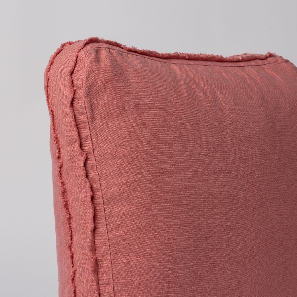 Poppy: close up of midweight linen pillow corner with raw edges trimming its gusset.