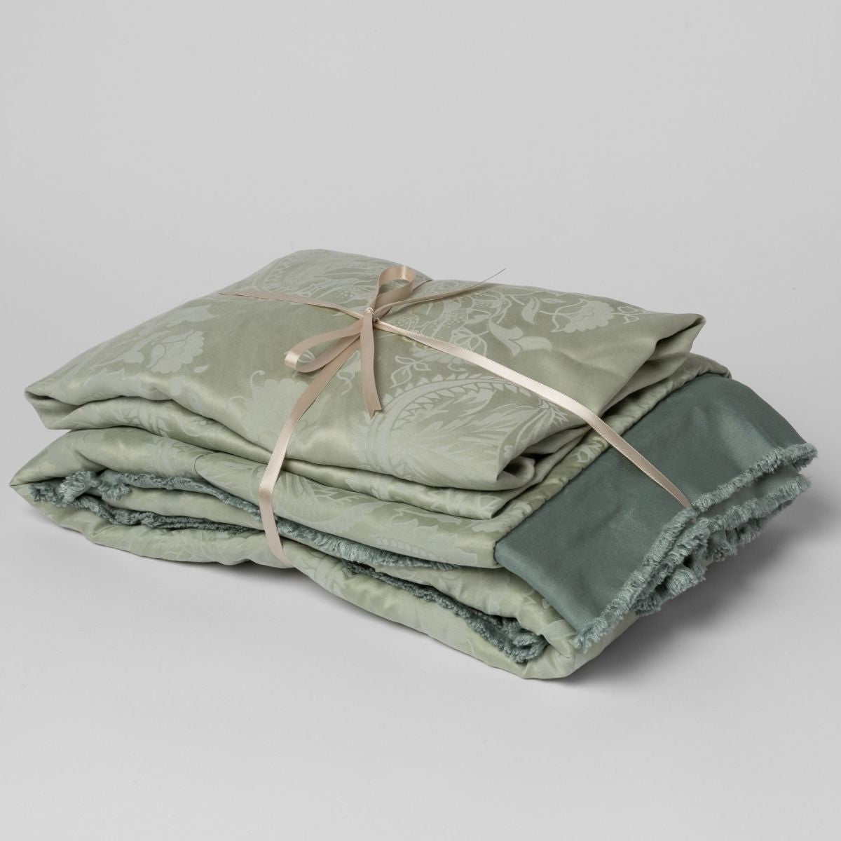 Eucalyptus: matching crib sheet and baby blanket bundled and tied with a ribbon against a white background.