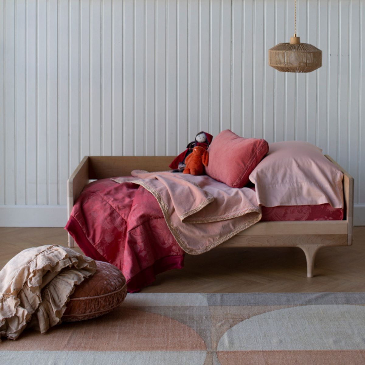 : a feminime toddler bed scene with pink and red bedding and throw pillows.