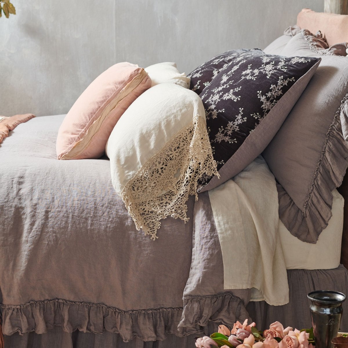 : Lynette sham in rich moonlight adds elegance and luxury to a linen bed embellished with ruffles and cotton lace - cropped side view.