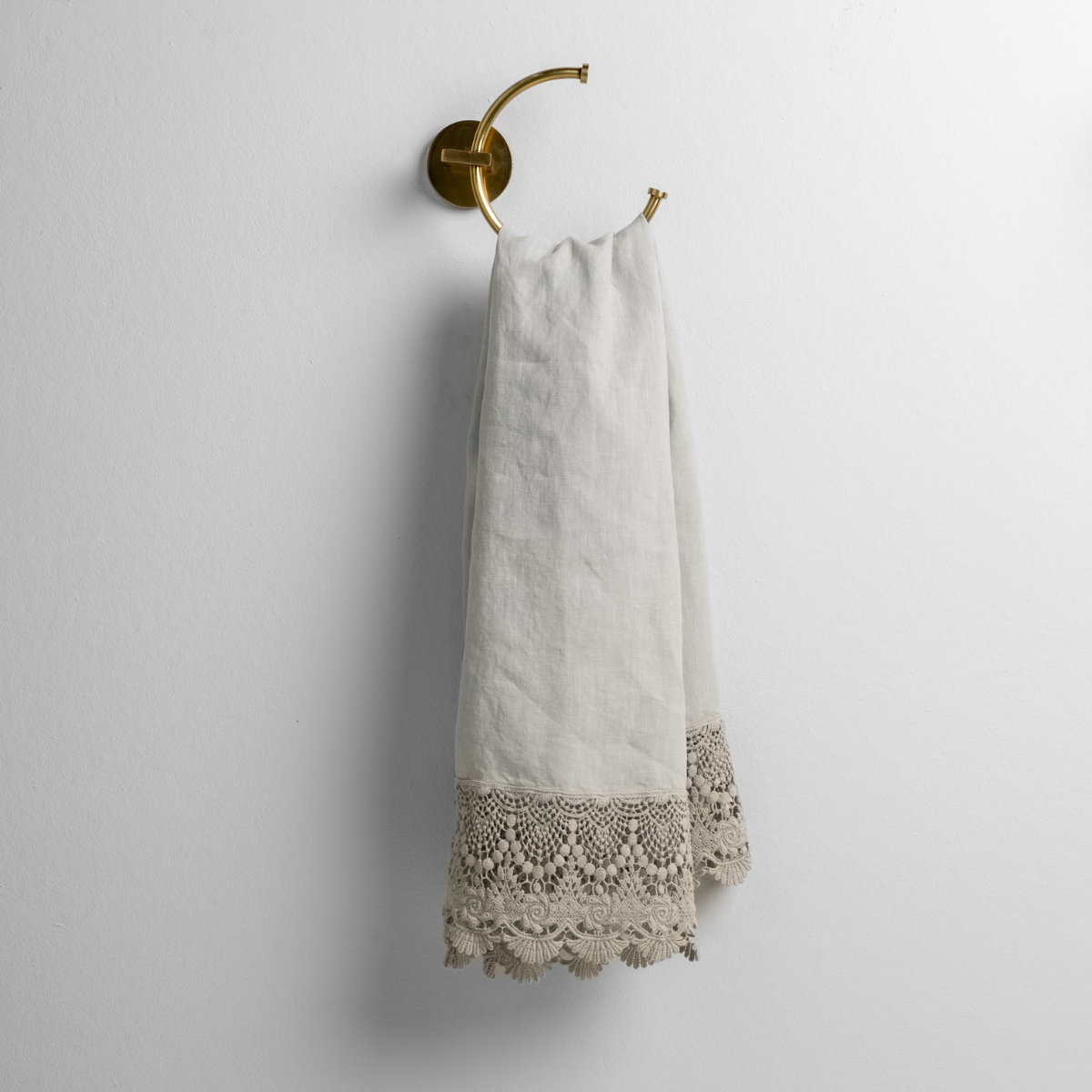 Cloud: linen with mattine lace trimmed guest towel on a decorative towel ring mounted on a white wall.