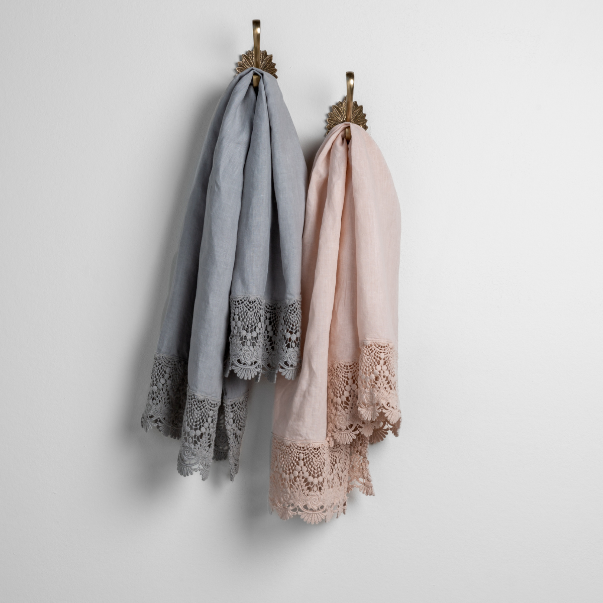 : pair of linen guest towels with mattine lace hanging from decorative towel hooks against a white wall - mineral and pearl.