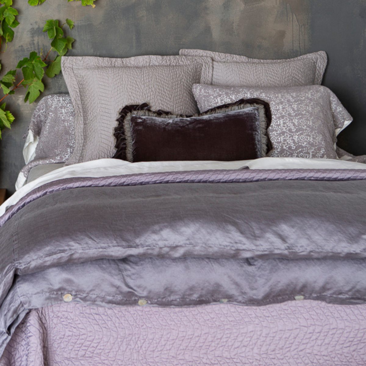 : cotton lace pillowcase covers staggered with monochromatic shams on a monochromatic bed shot from the end of bed view.