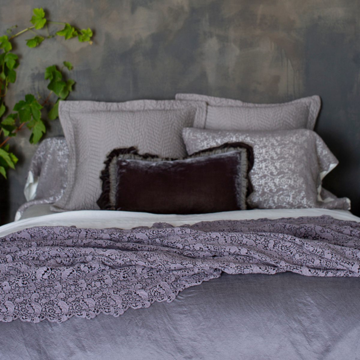 : lace bed scarf on monochromatic bed shot from the foot of the bed with the pillows at the head of the bed slightly out of focus.