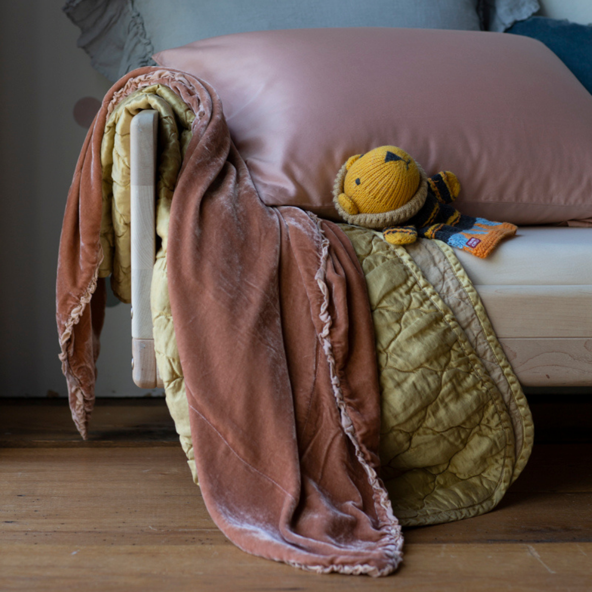 : silk velvet baby blanket with charmeuse trim with quilted charmeuse blanket and sleeping pillow on a natural colored toddler bed with a small stuffed animal in the shot.