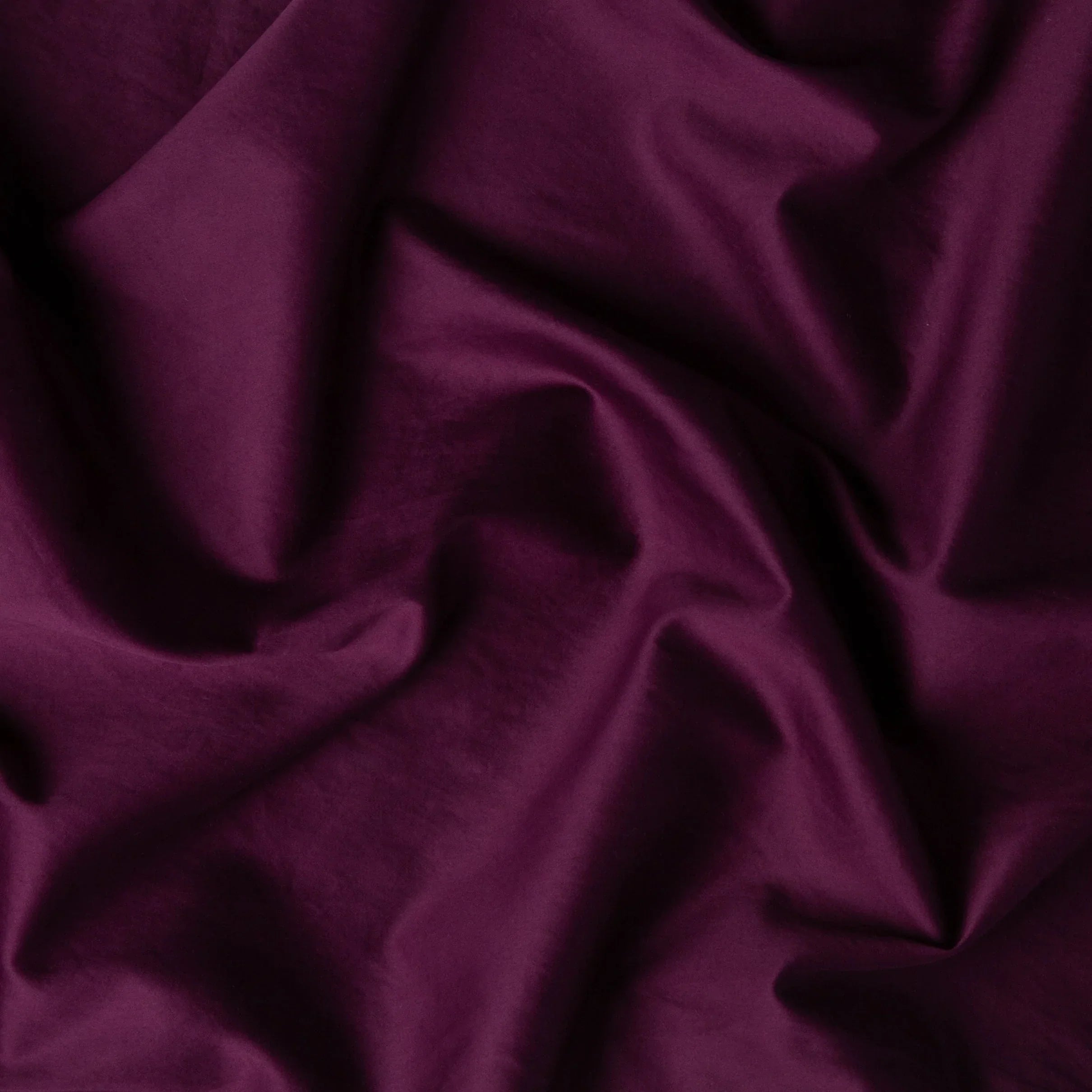 Fig: A close up of cotton sateen fabric in fig, a richly saturated purple-garnet.
