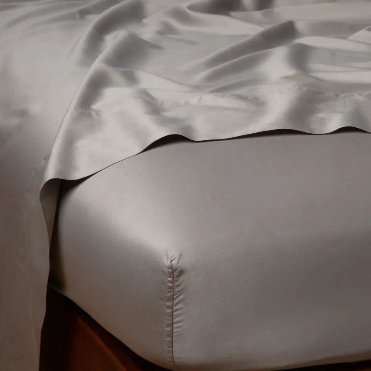 Fog: Cotton sateen flat sheet draped over matching fitted sheet. Shown from the top corner, the flat sheet is rumpled, highlighting the shine of the fabric.