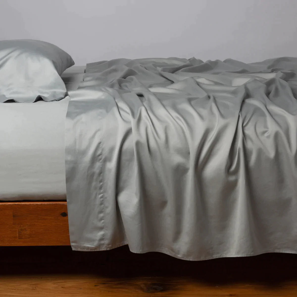 Mineral: Cotton sateen sleeping pillow, on a bed with matching sheets - side view.