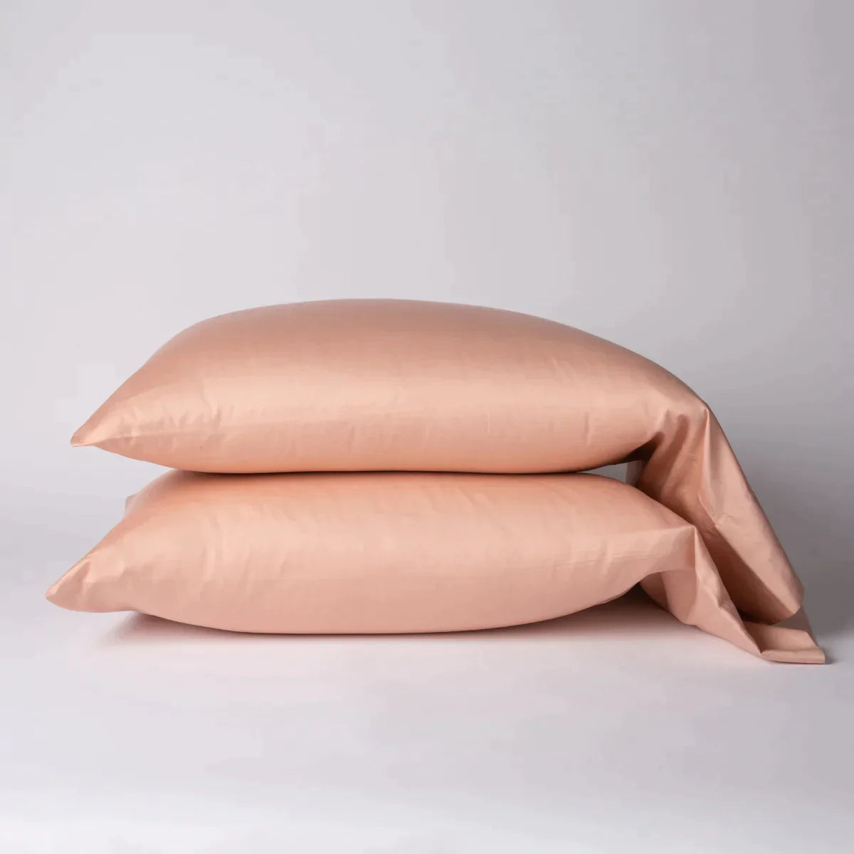Rouge: Two cotton sateen sleeping pillows, stacked neatly against a white backdrop - side view.