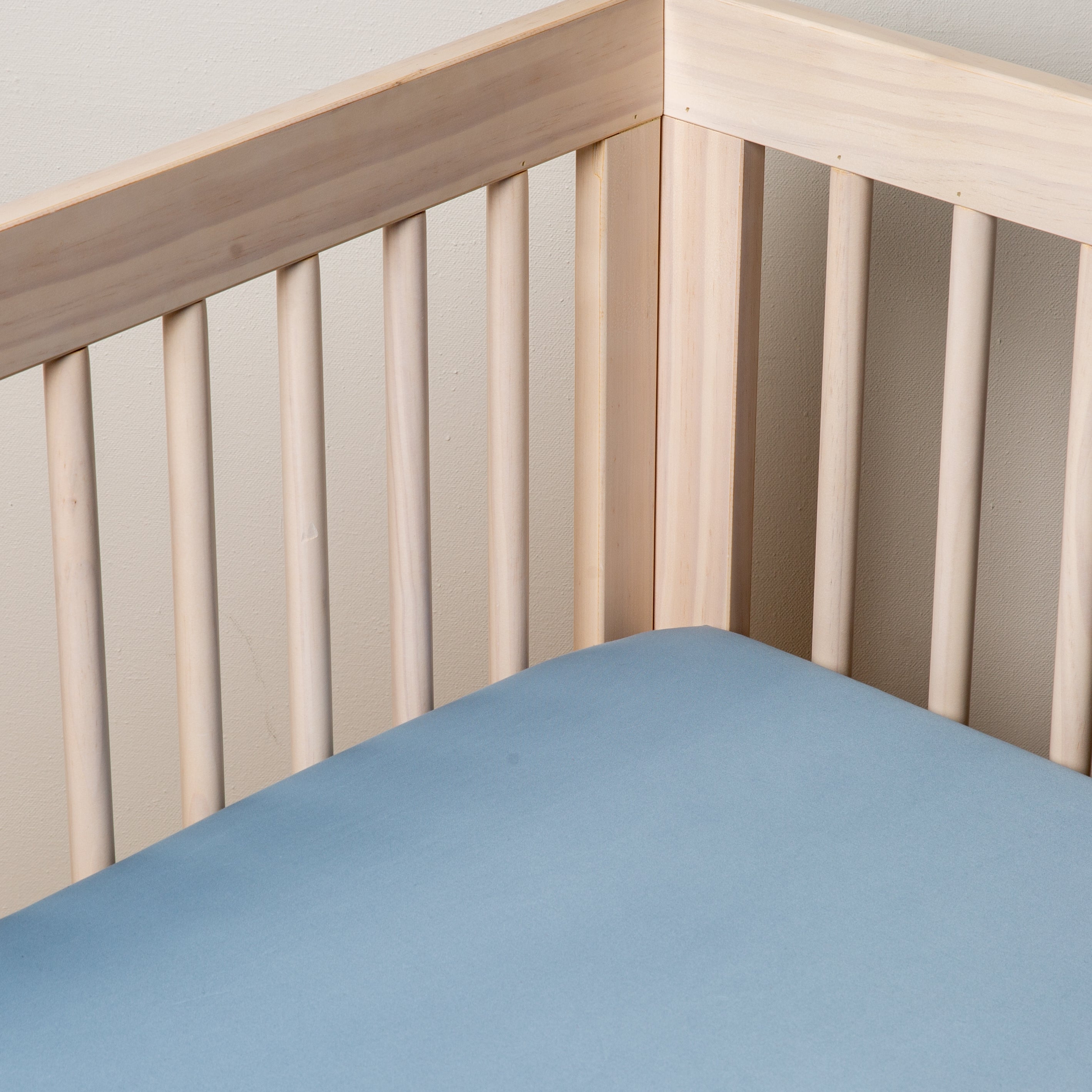 Tahoe Blue: Cotton sateen crib sheet shown from a slight overhead angle into an inside corner of a crib.