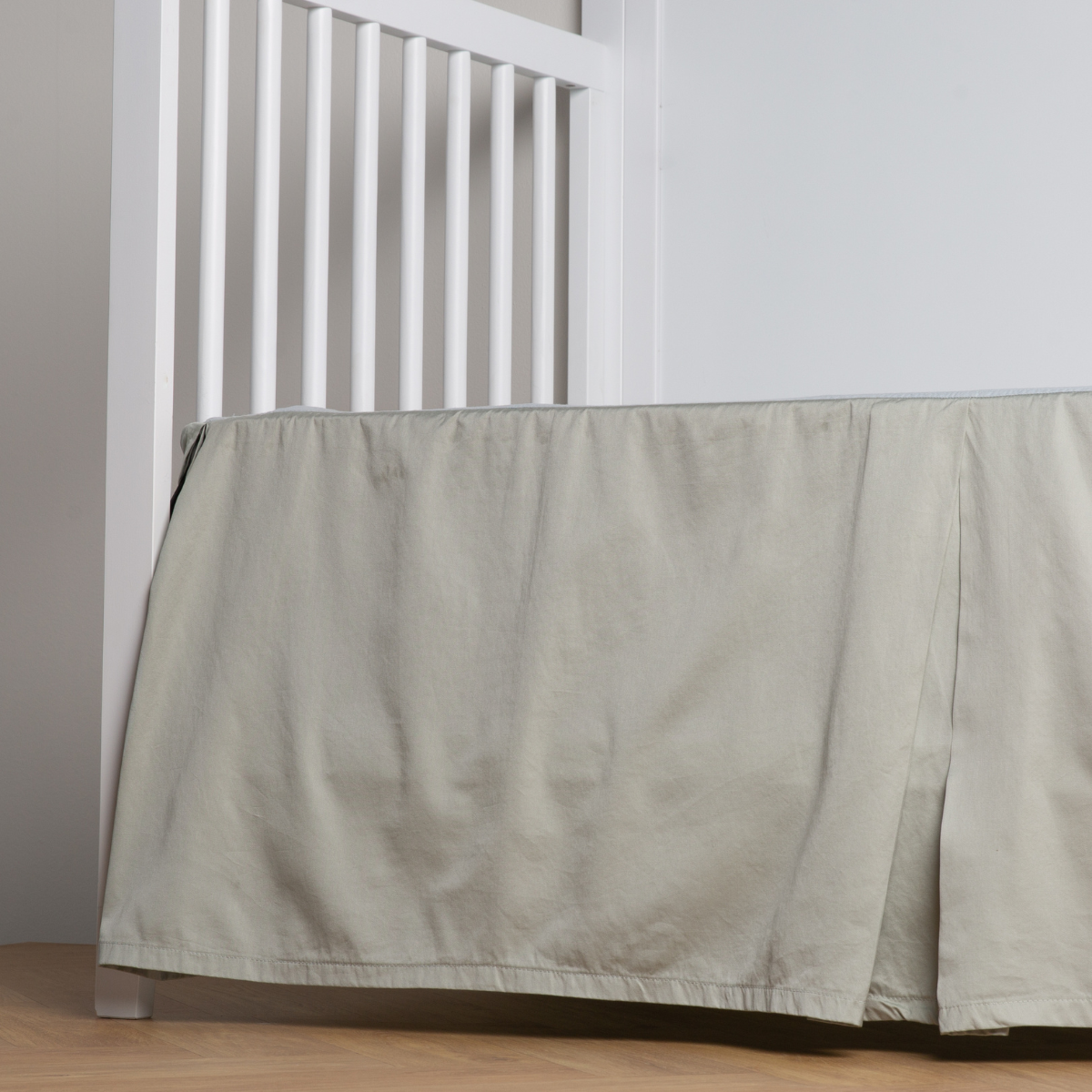 Eucalyptus: cotton sateen cribi skirt with a center pleat shown straight on from a slight angle in a crib without a crib mattress.