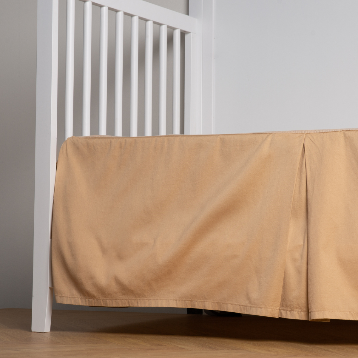 Honeycomb: cotton sateen cribi skirt with a center pleat shown straight on from a slight angle in a crib without a crib mattress.