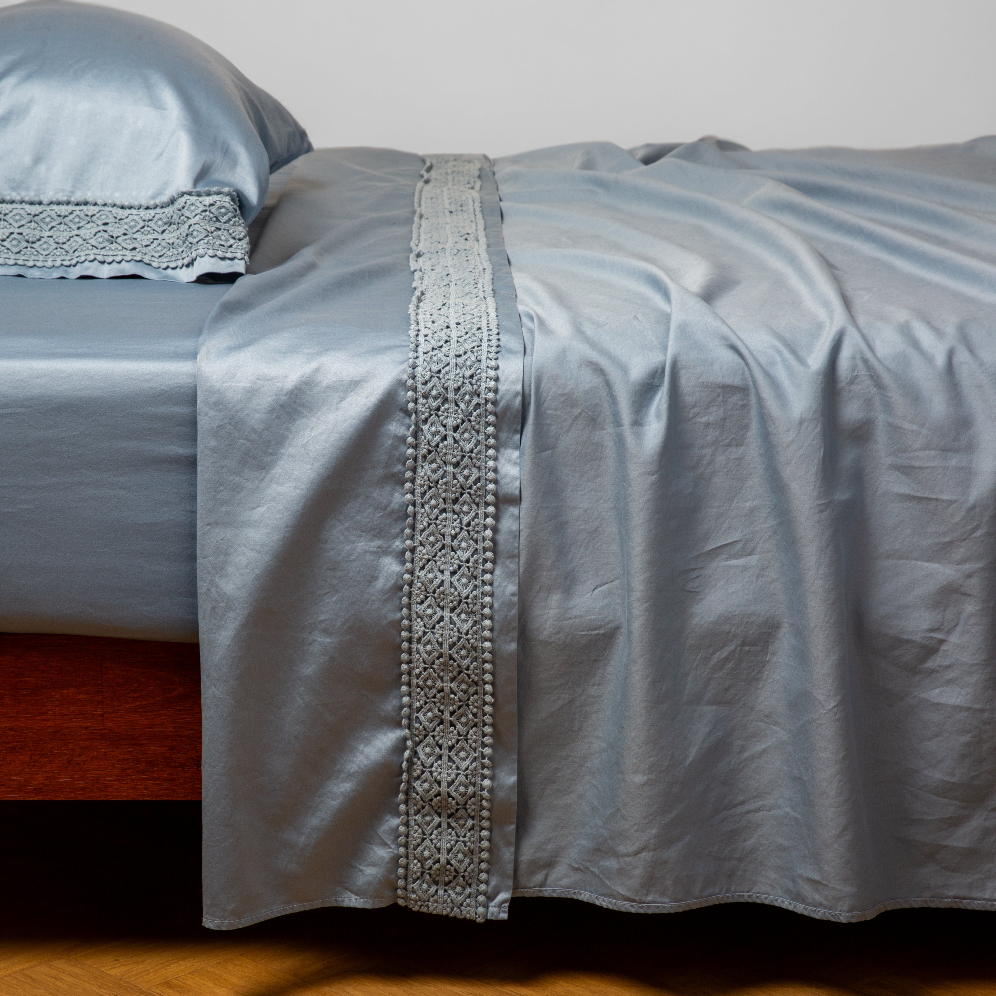 Tahoe Blue: Cotton sateen fitted sheet shown with matching flat sheet and sleeping pillow - side view.