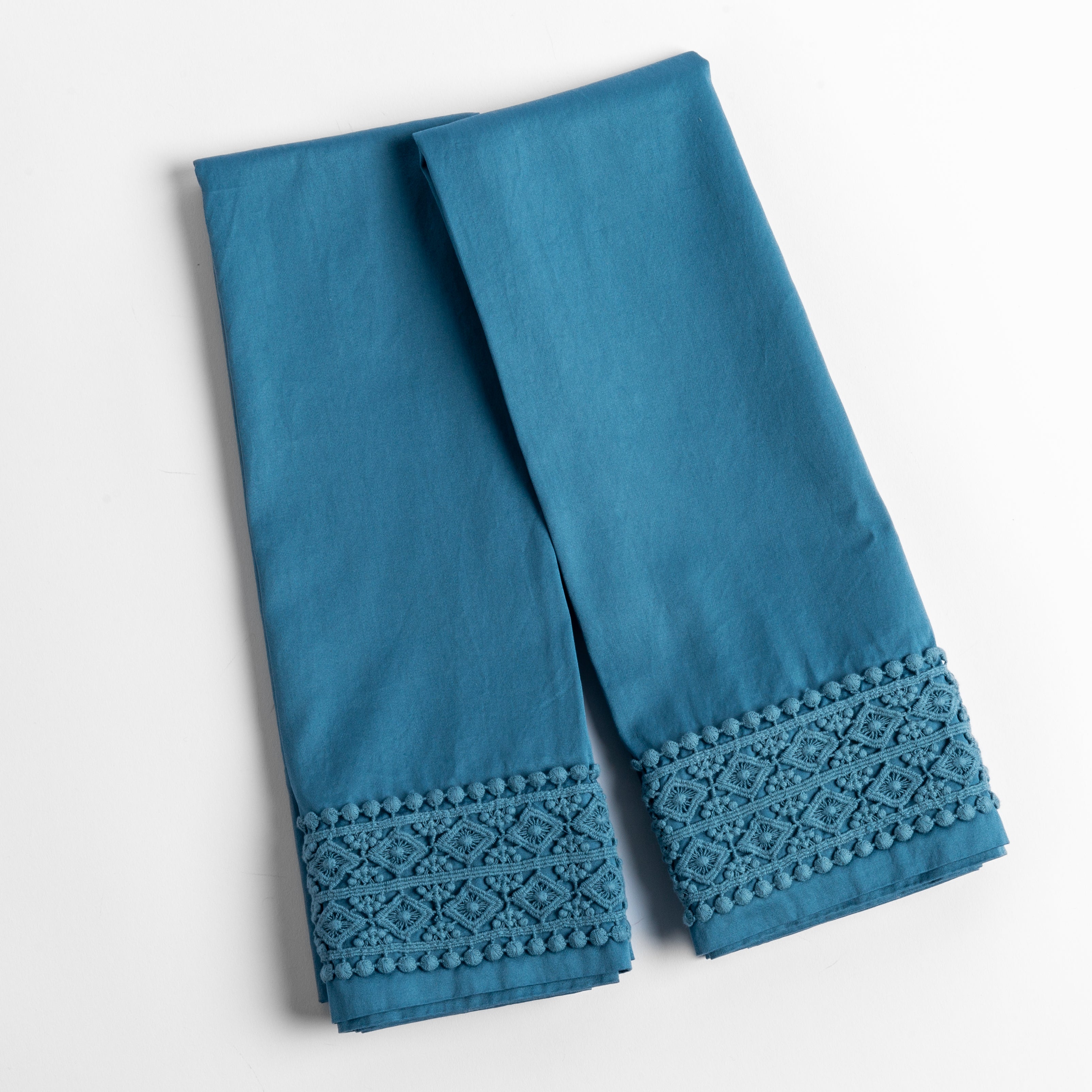 An overhead shot of a folded pair of lace trimmed pillowcases shown side by side and slightly overlapping.