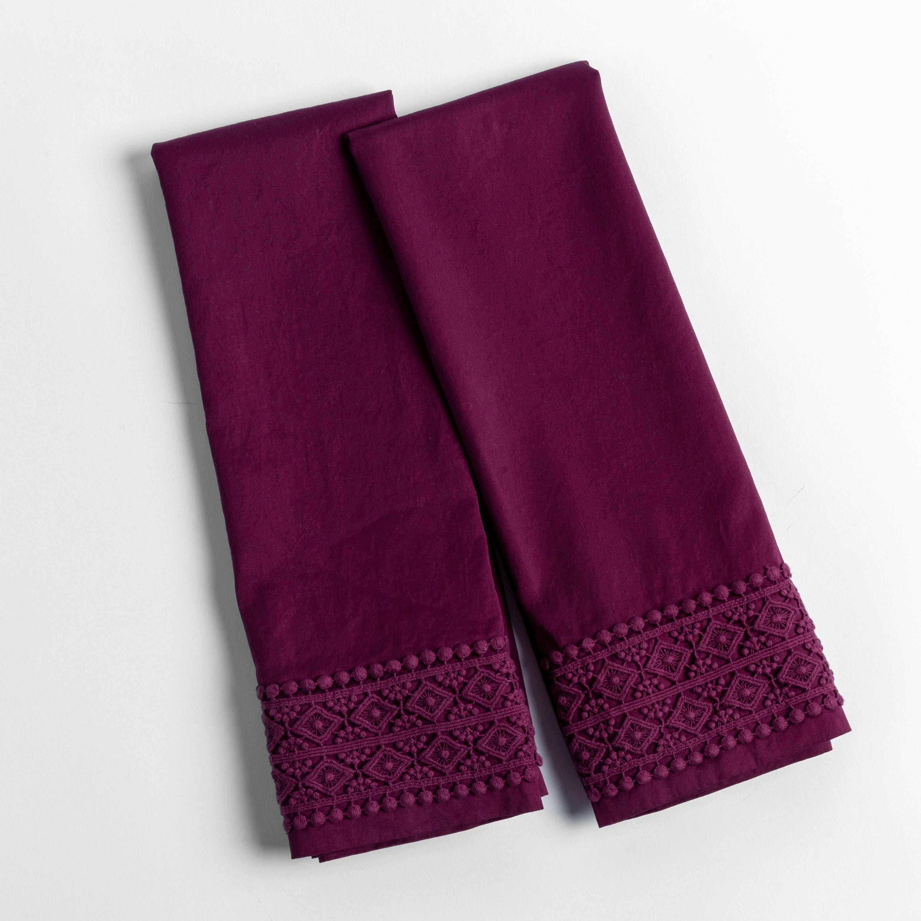 An overhead shot of a folded pair of lace trimmed pillowcases shown side by side and slightly overlapping.