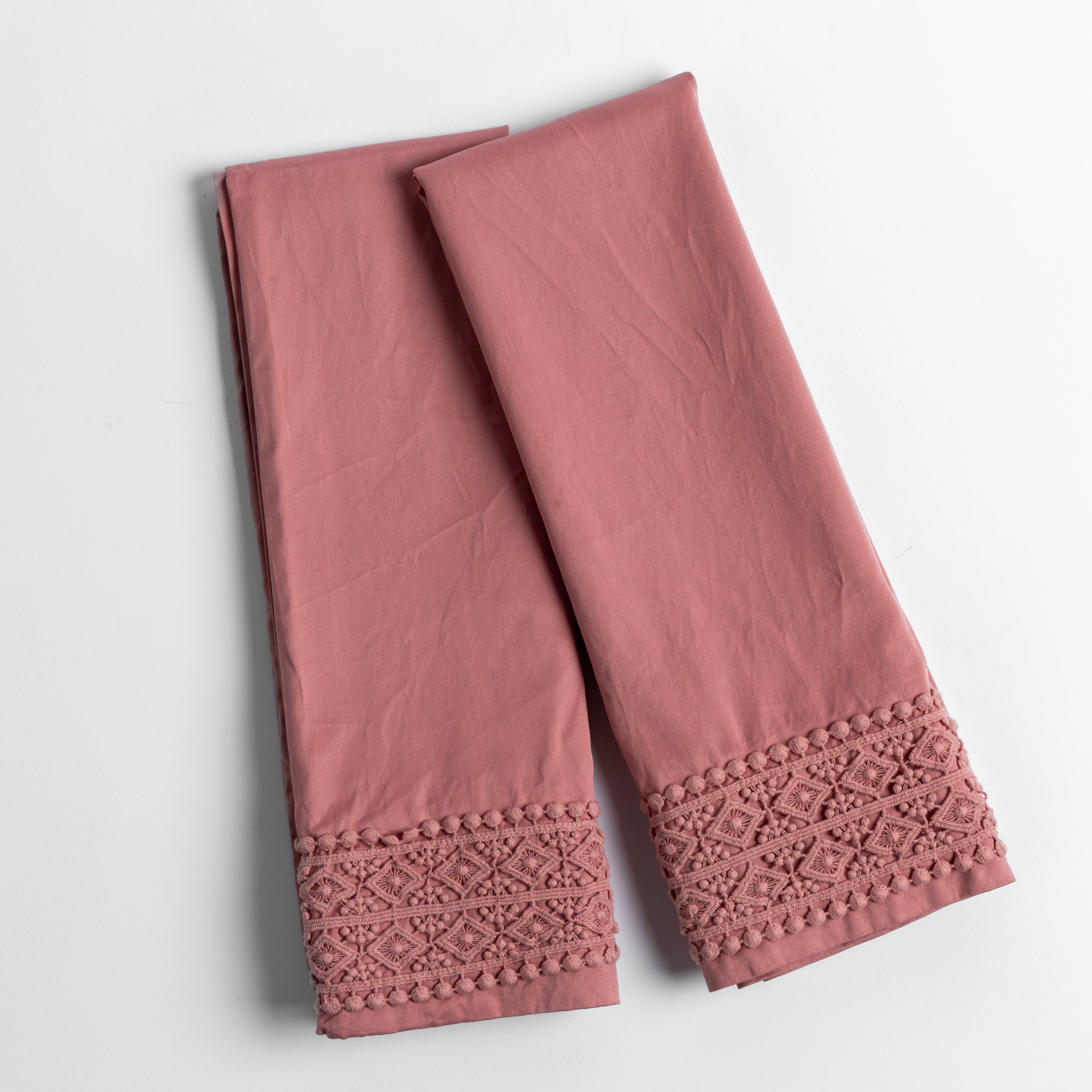 An overhead shot of a folded pair of lace trimmed pillowcases shown side by side and slightly overlapping.