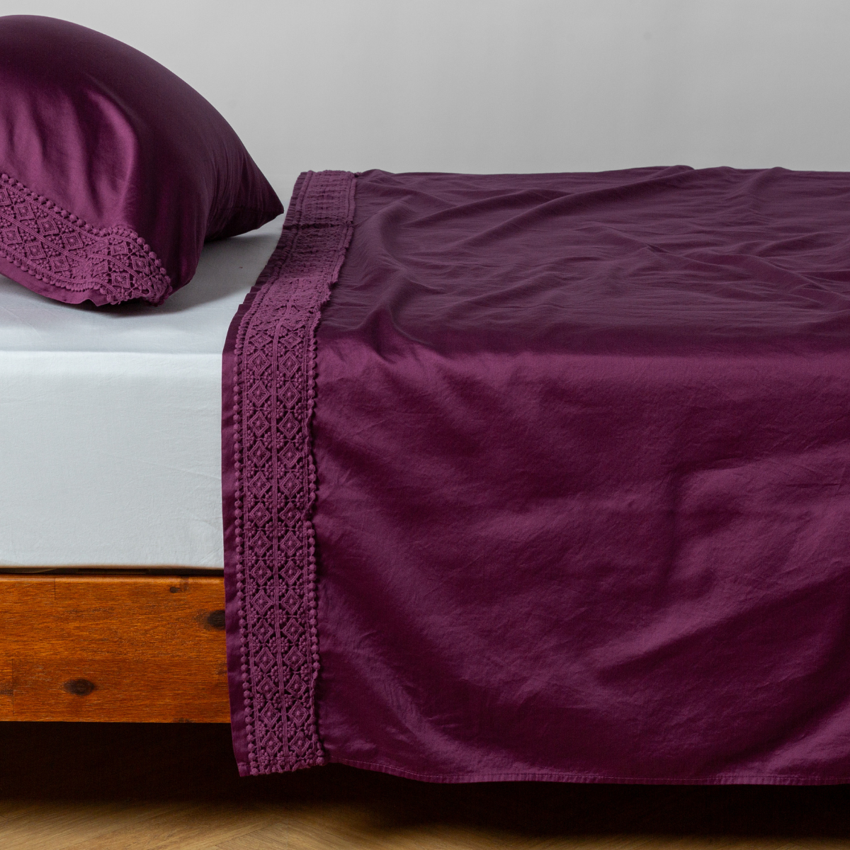 Matching lace trimmed cotton sateen flat sheet and pillowcase shown with a winter white fitted sheet - side view.