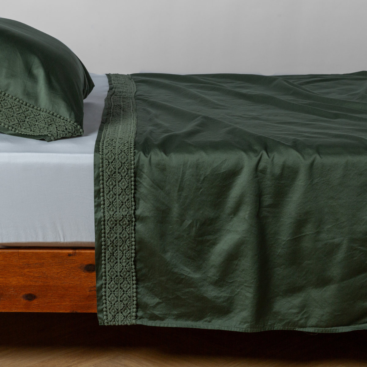 Matching lace trimmed cotton sateen flat sheet and pillowcase shown with a winter white fitted sheet - side view.