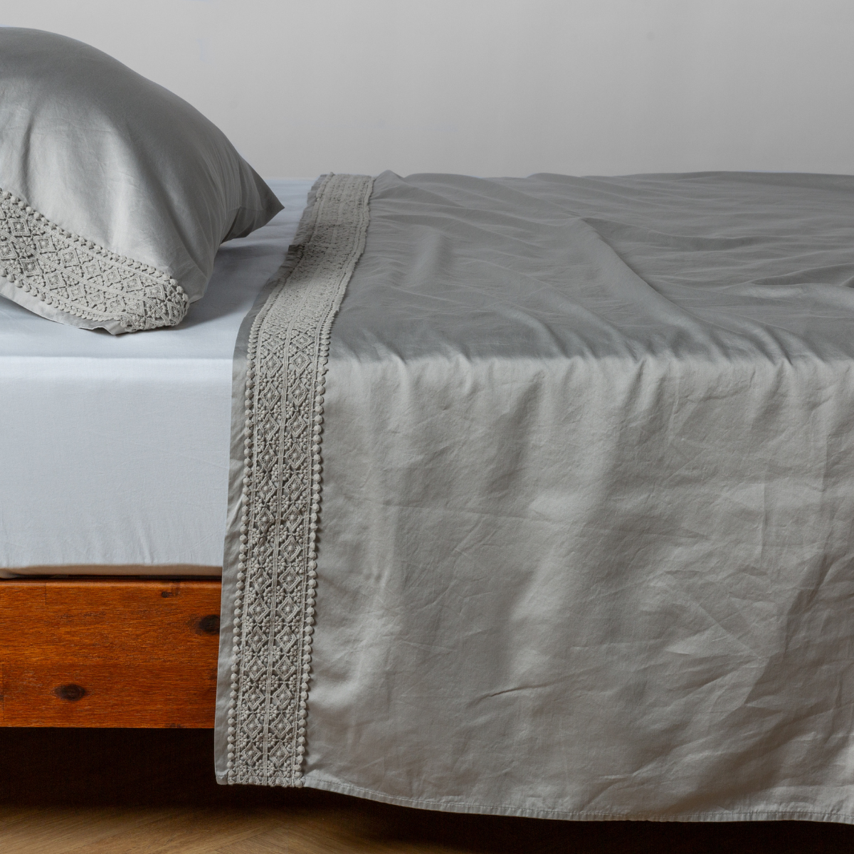 Matching lace trimmed cotton sateen flat sheet and pillowcase shown with a winter white fitted sheet - side view.