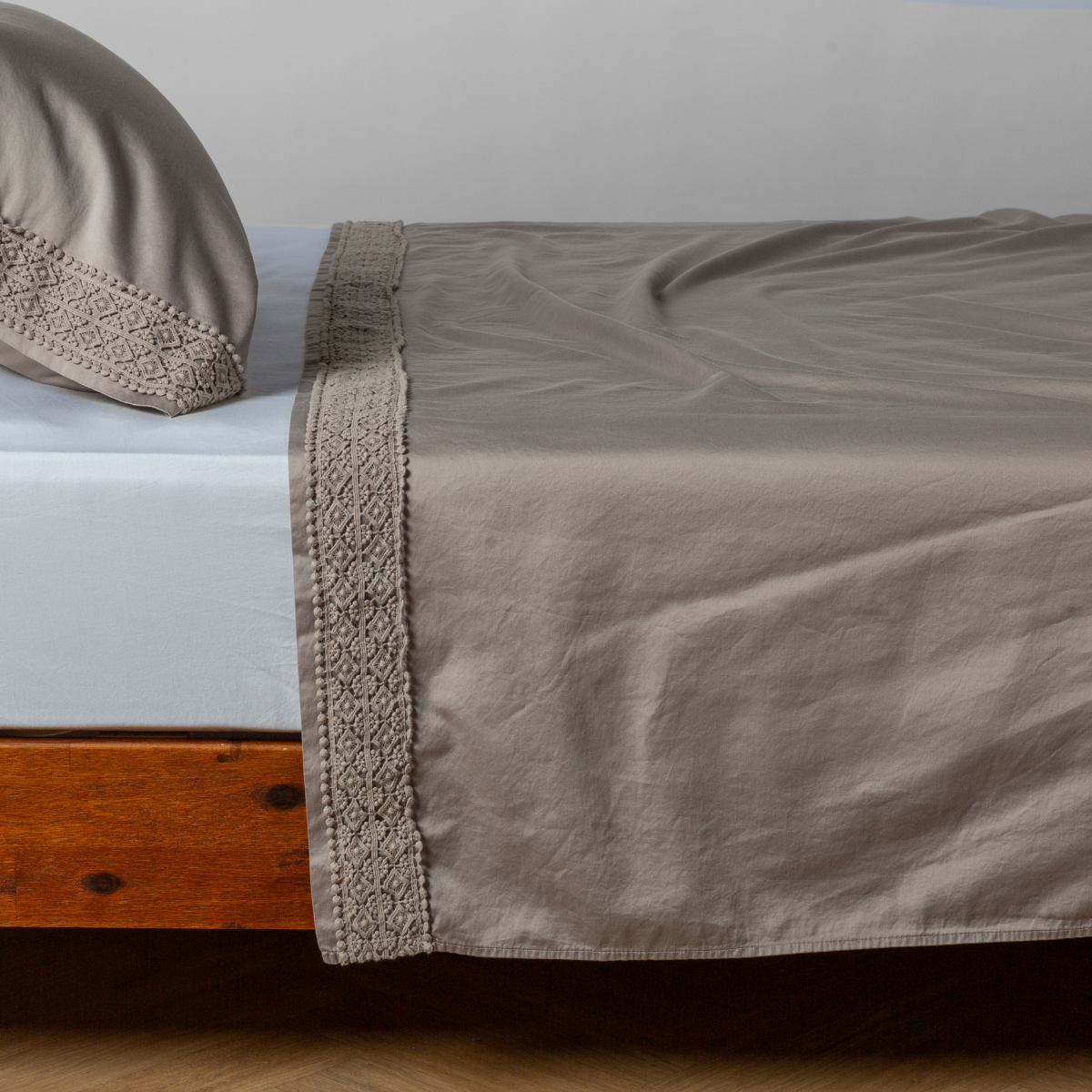 Matching lace trimmed cotton sateen flat sheet and pillowcase shown with a winter white fitted sheet - side view.