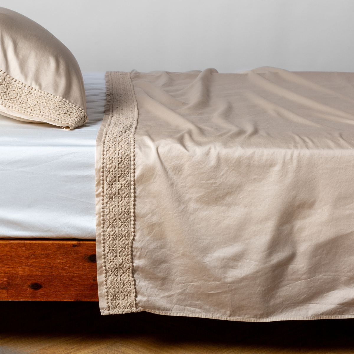 Matching lace trimmed cotton sateen flat sheet and pillowcase shown with a winter white fitted sheet - side view.