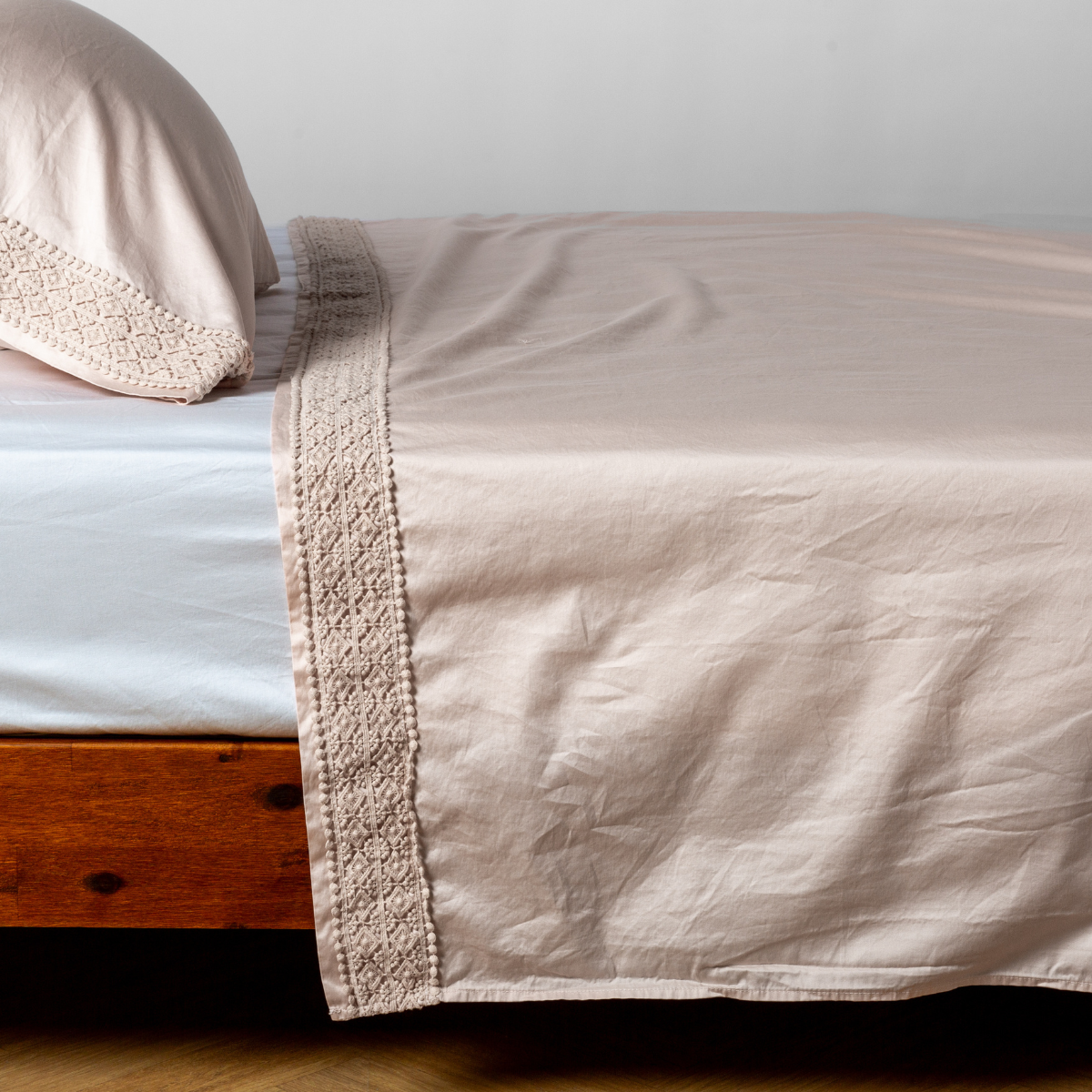 Matching lace trimmed cotton sateen flat sheet and pillowcase shown with a winter white fitted sheet - side view.