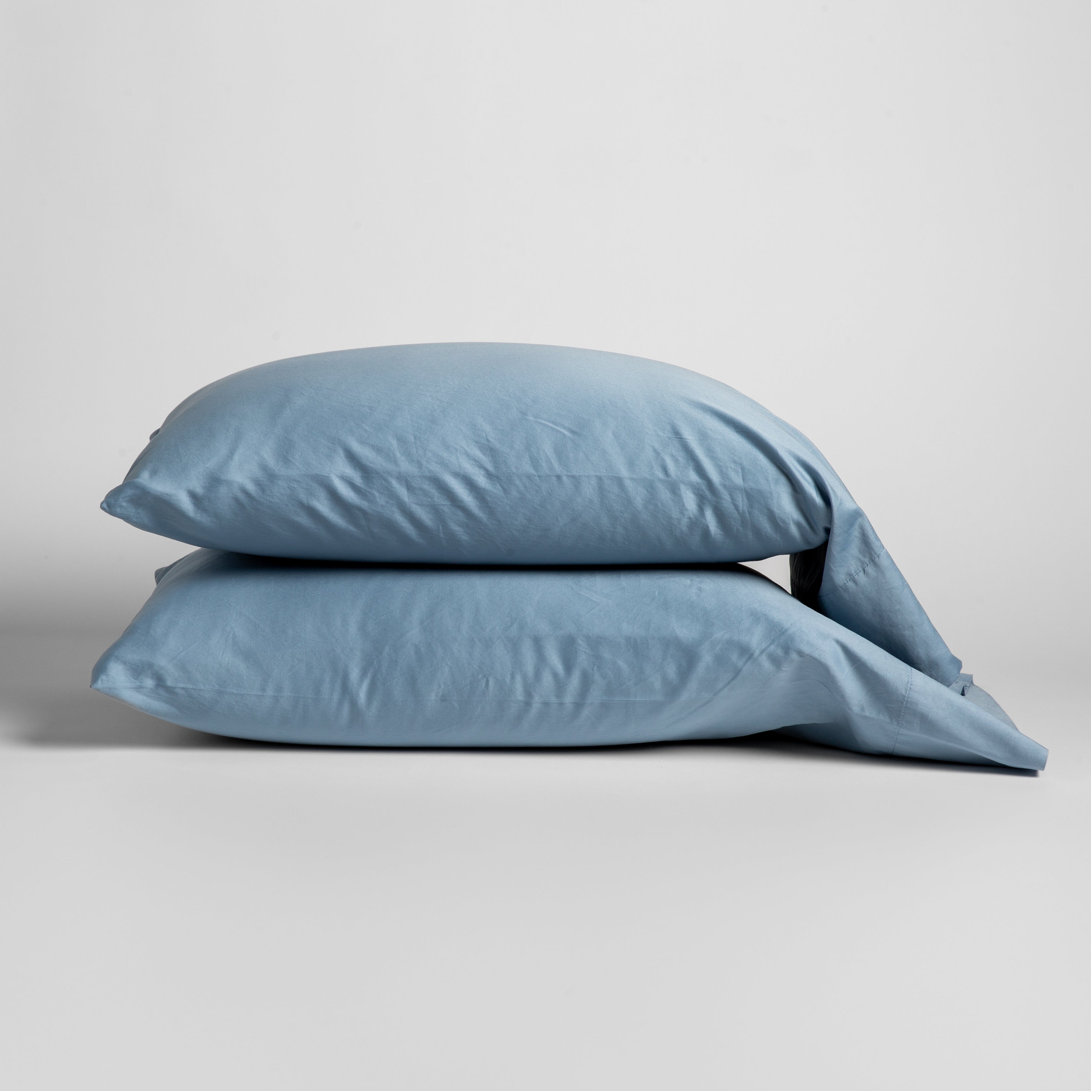 Tahoe Blue: Two cotton sateen sleeping pillows, stacked neatly against a white backdrop - side view.
