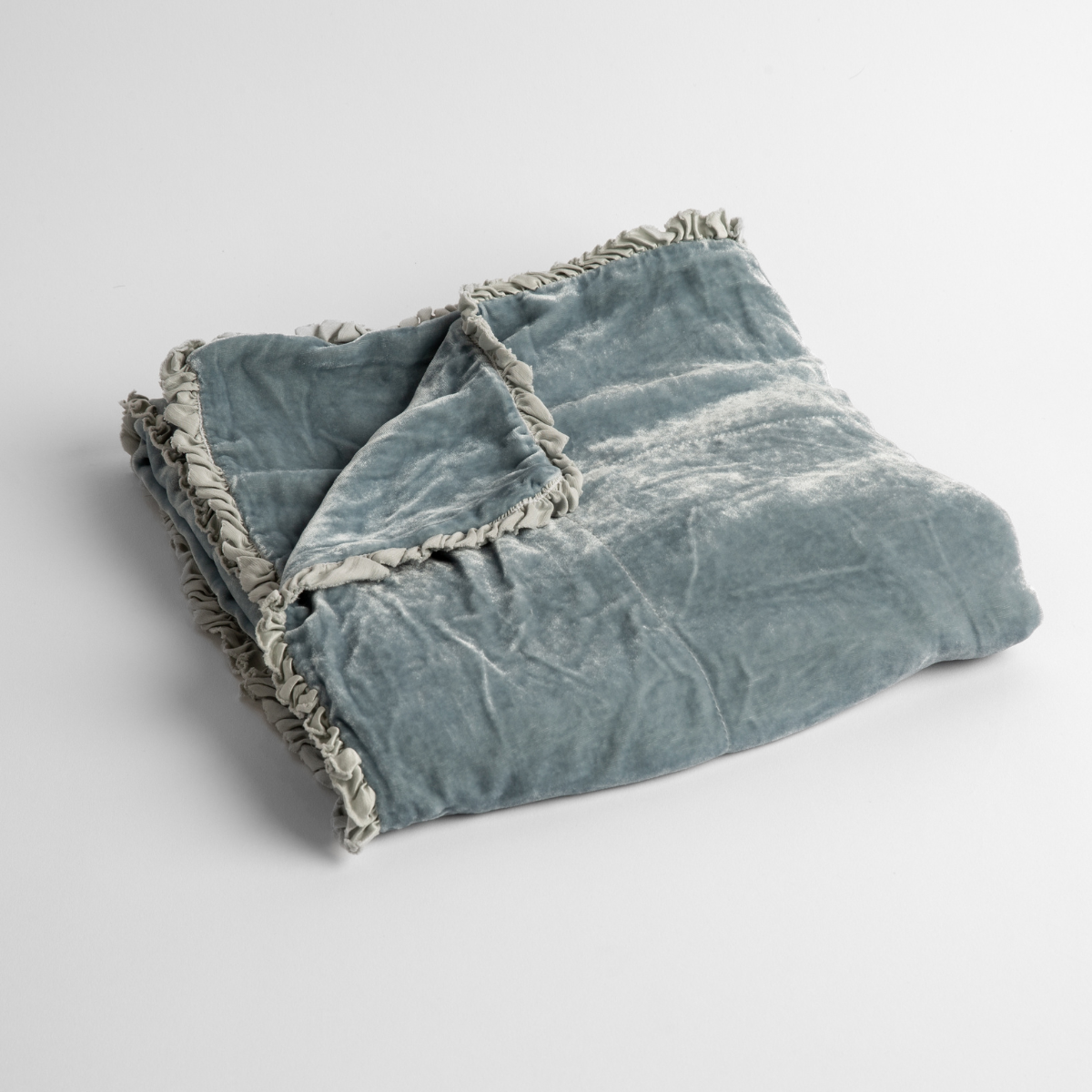 Cloud: silk velvet baby blanket with charmeuse trim shown slightly overhead with a corner folded back to show trim detail against a white background.