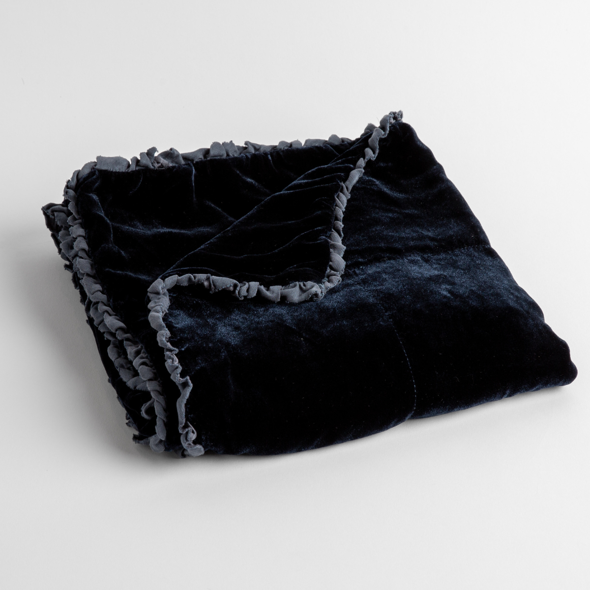 Midnight: silk velvet baby blanket with charmeuse trim shown slightly overhead with a corner folded back to show trim detail against a white background.