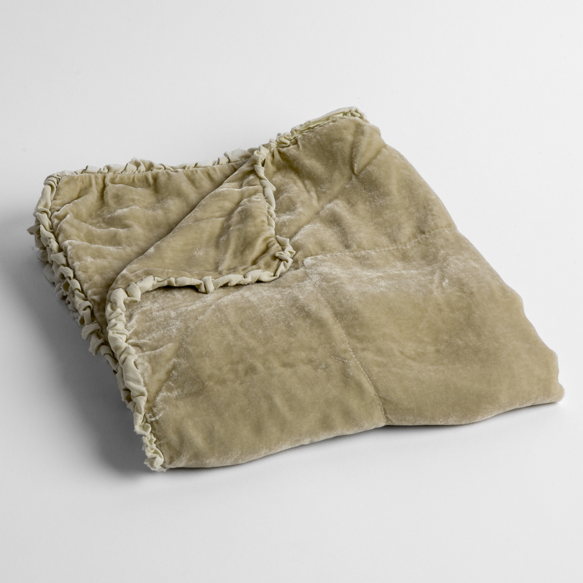 Parchment: silk velvet baby blanket with charmeuse trim shown slightly overhead with a corner folded back to show trim detail against a white background.