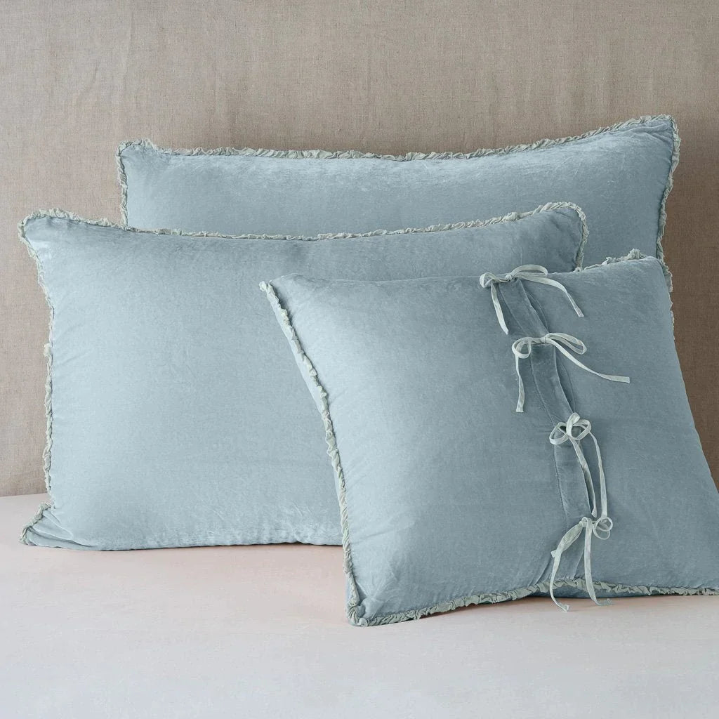 Cloud: Silk velvet shams with a petite ruffle leaning upright against a neutral headboard. The front sham is backwards, showcasing the charmeuse tie closures.
