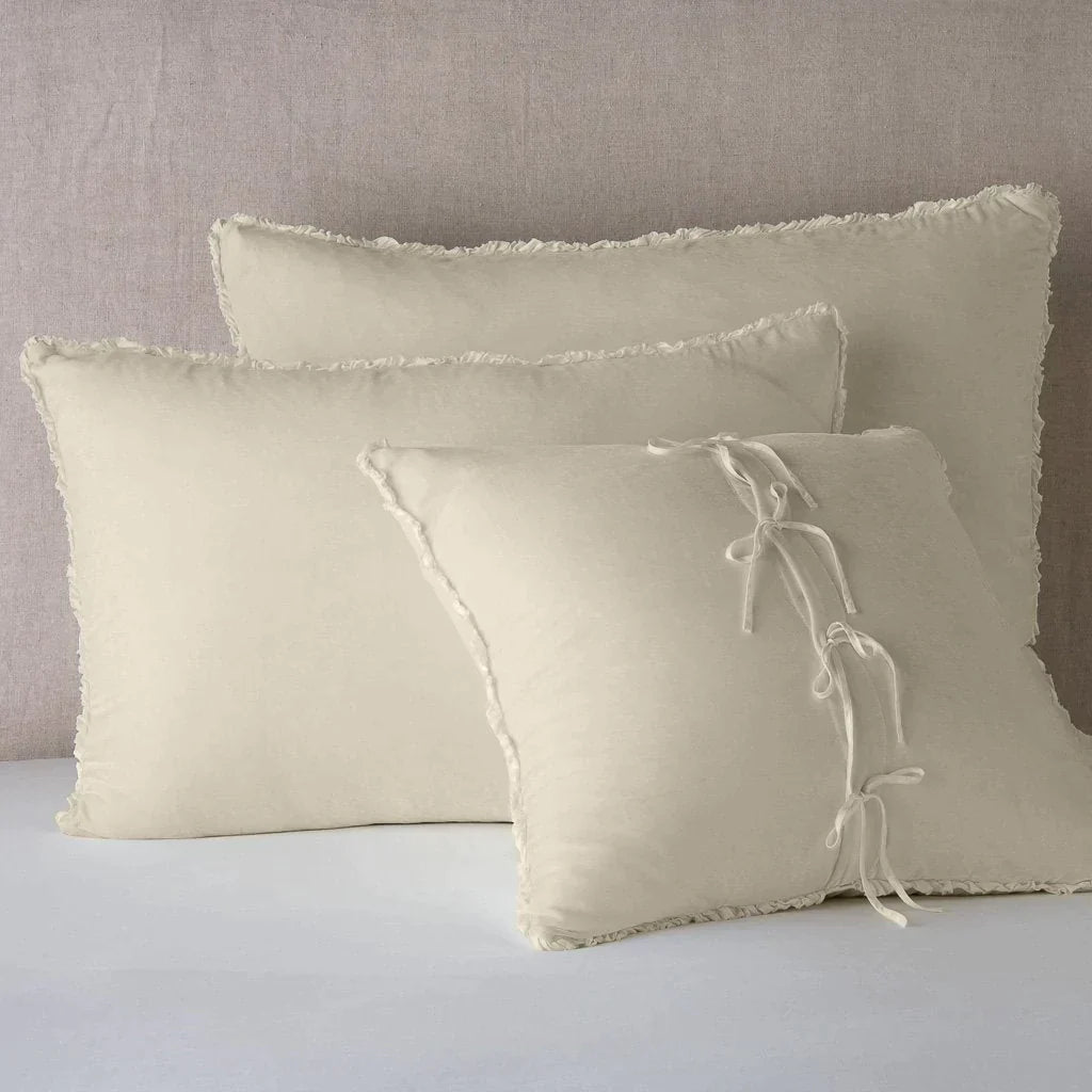 Parchment: Silk velvet shams with a petite ruffle leaning upright against a neutral headboard. The front sham is backwards, showcasing the charmeuse tie closures.