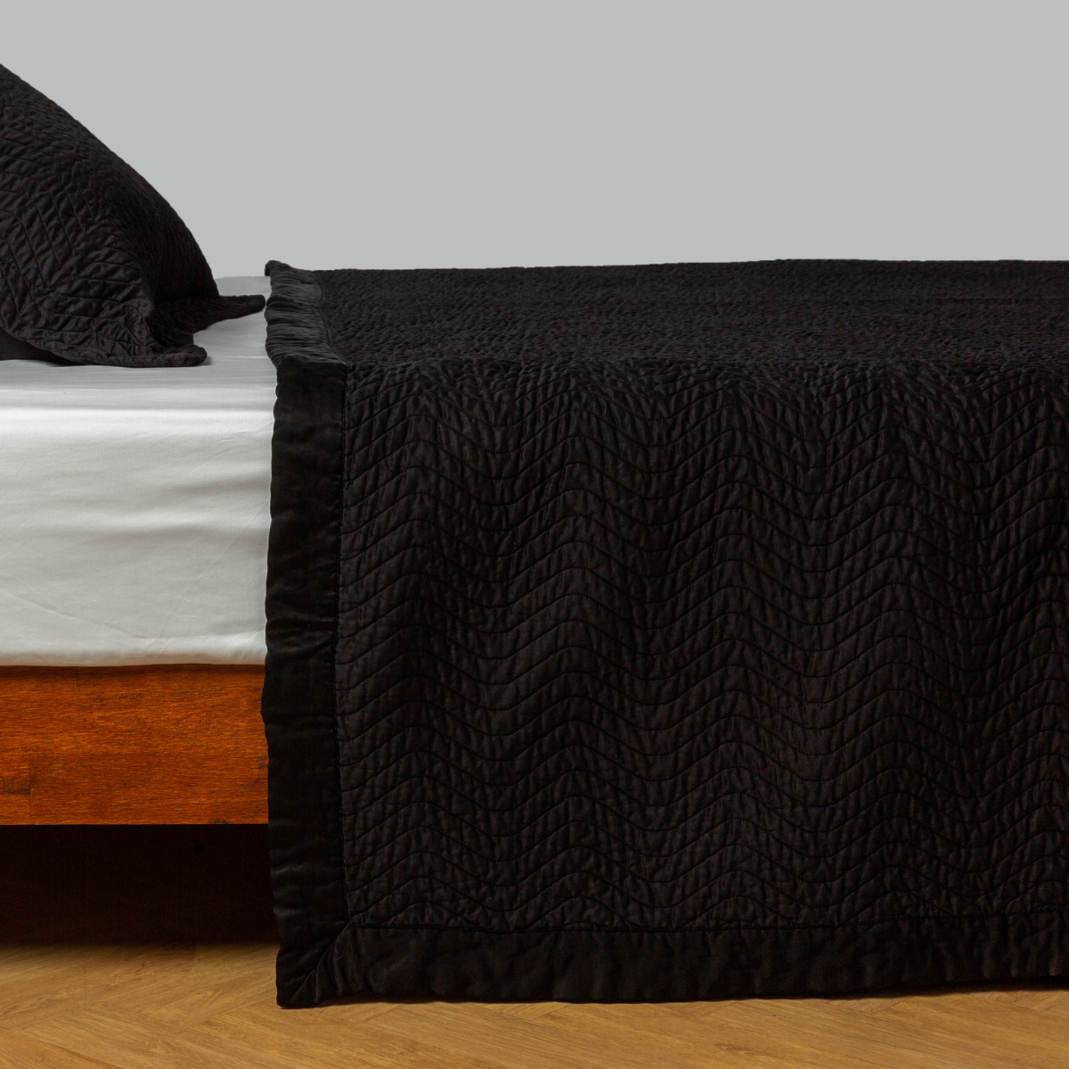 Corvino: quilted cotton sateen coverlet with matching sham on a winter white fitted sheet - side view.