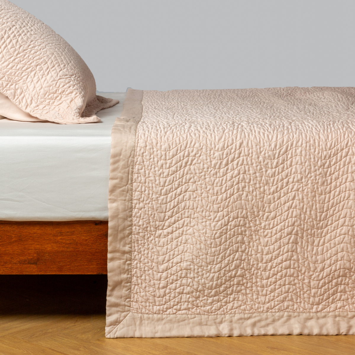 Pearl: quilted cotton sateen coverlet with matching sham on a winter white fitted sheet - side view.