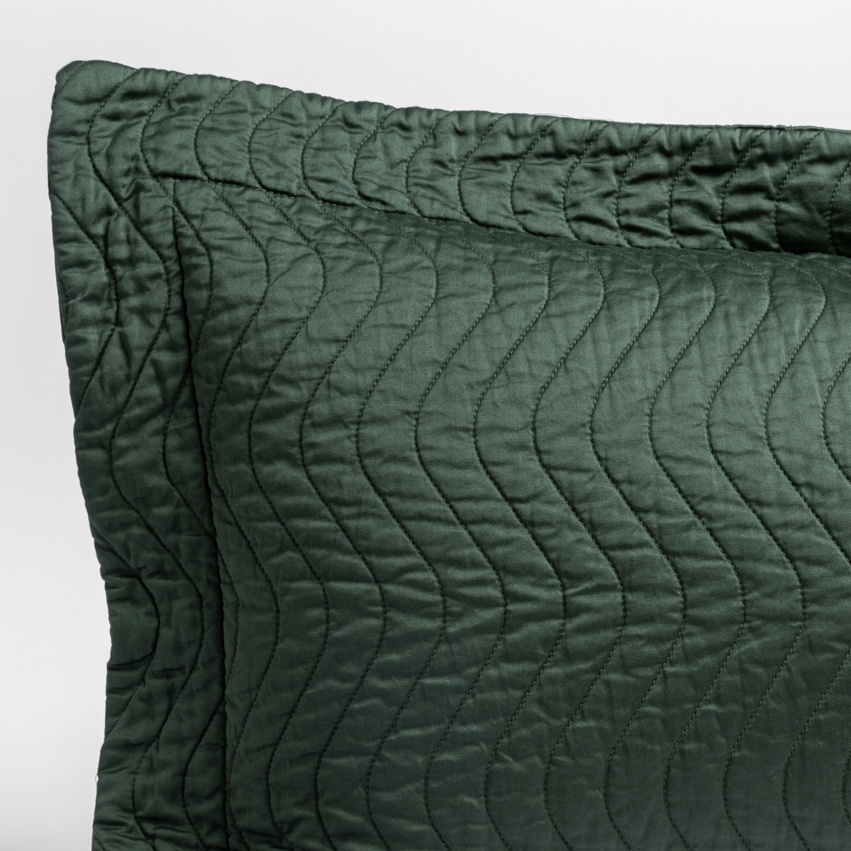 Juniper: a close up of a pillow corner showing the flange framing quilted cotton sateen shot against a white background.