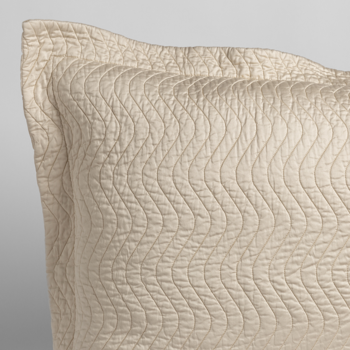 Parchment: a close up of a pillow corner showing the flange framing quilted cotton sateen shot against a white background.