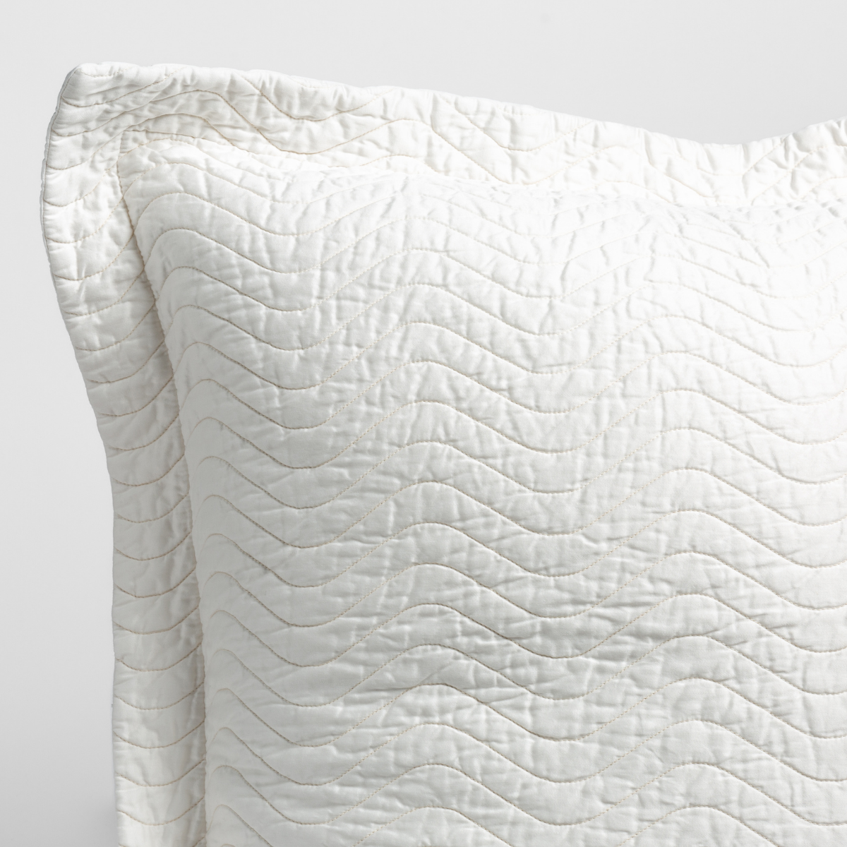 Winter White: close up of the corner of a quilted cotton sateen pillow sham - shot against a white background.