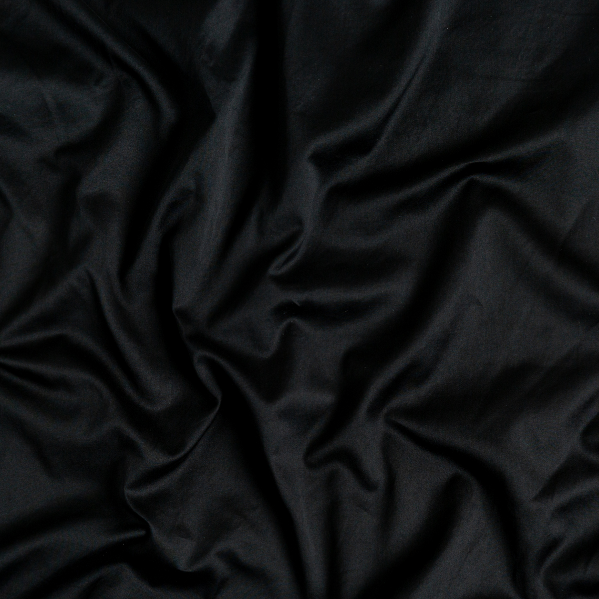 Corvino: A close up of cotton sateen fabric in Corvino, a black tone.