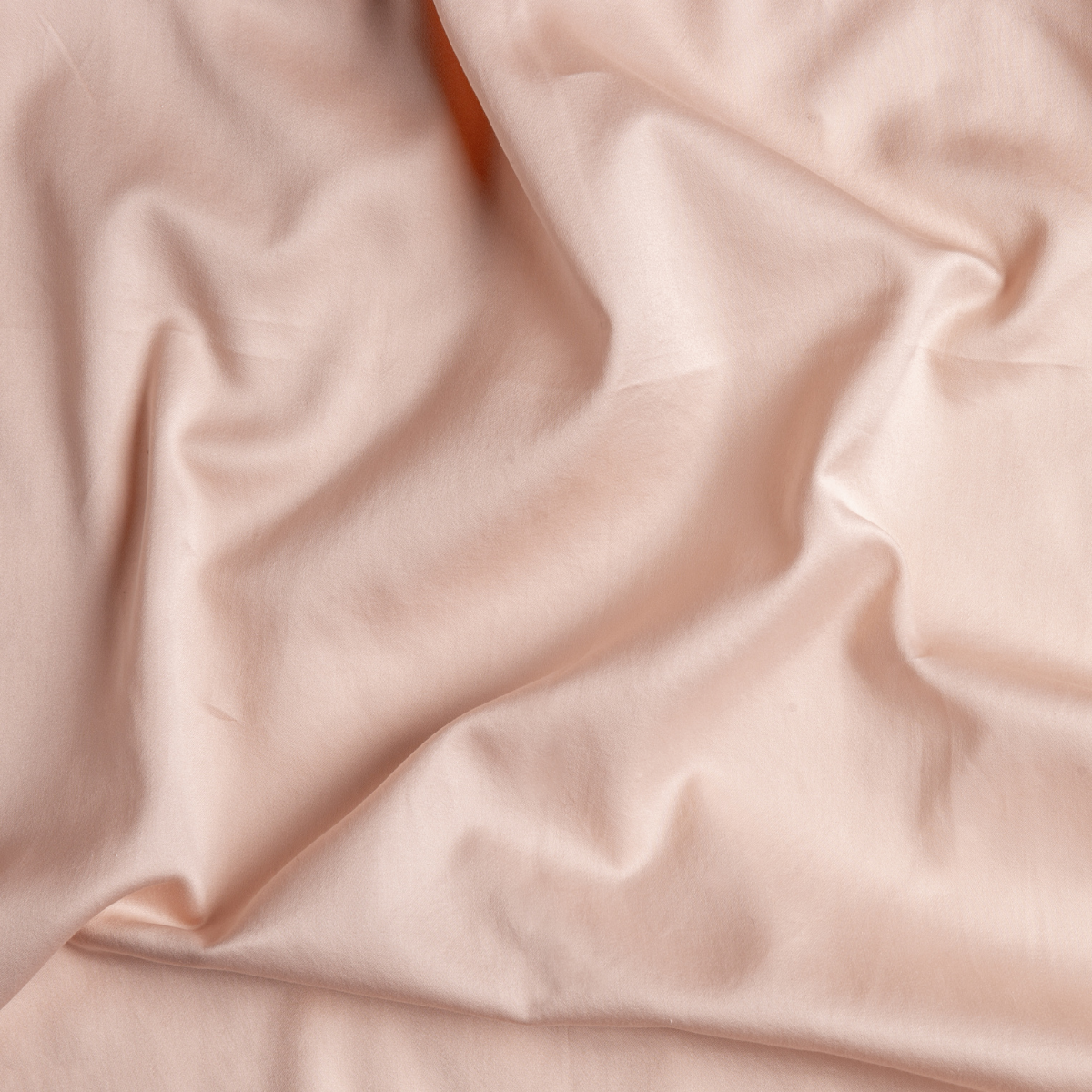 Pearl: A close up of cotton sateen fabric in pearl, a nude-like, soft rose pink tone.