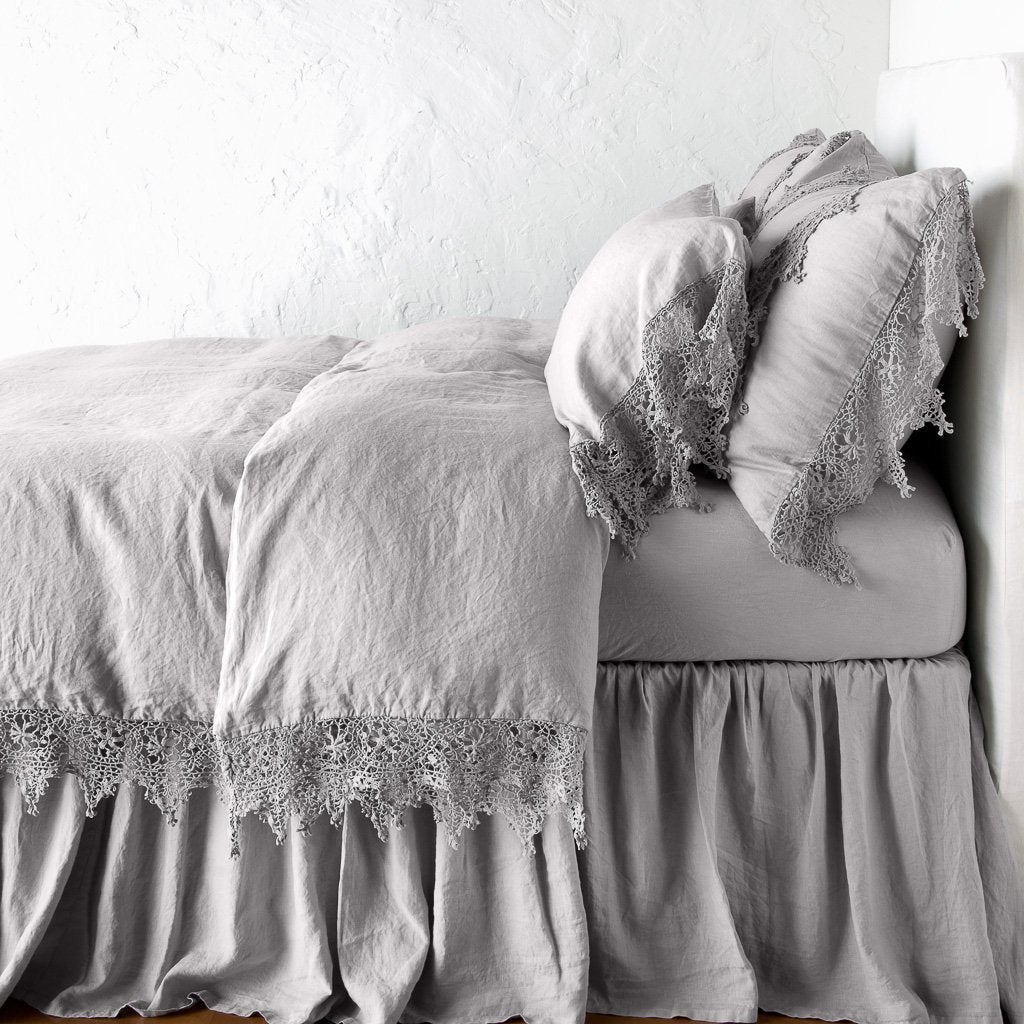 : Frida pillowcase in fog on a monochromatic linen bed - side view.