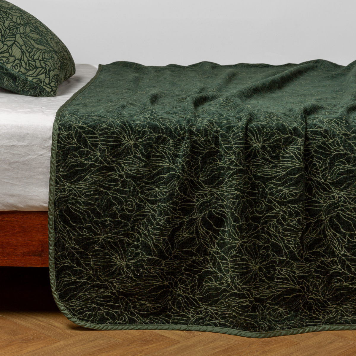 Juniper: side view of the chenille jacquard side of a bedspread with the cotton jacquard side showing on the matching sham β shown with a winter white fitted sheet.
