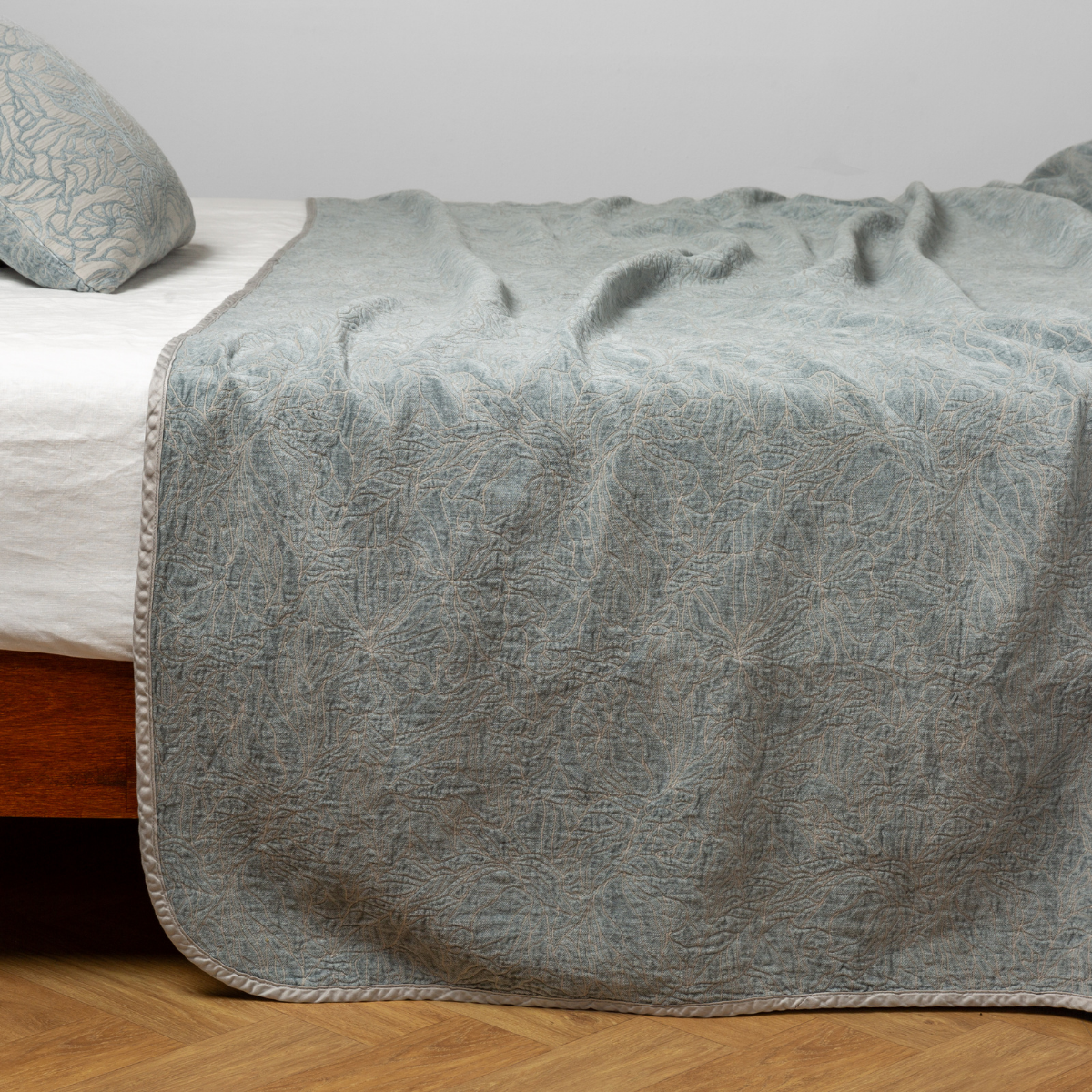 Mineral: side view of the chenille jacquard side of a bedspread with the cotton jacquard side showing on the matching sham β shown with a winter white fitted sheet.