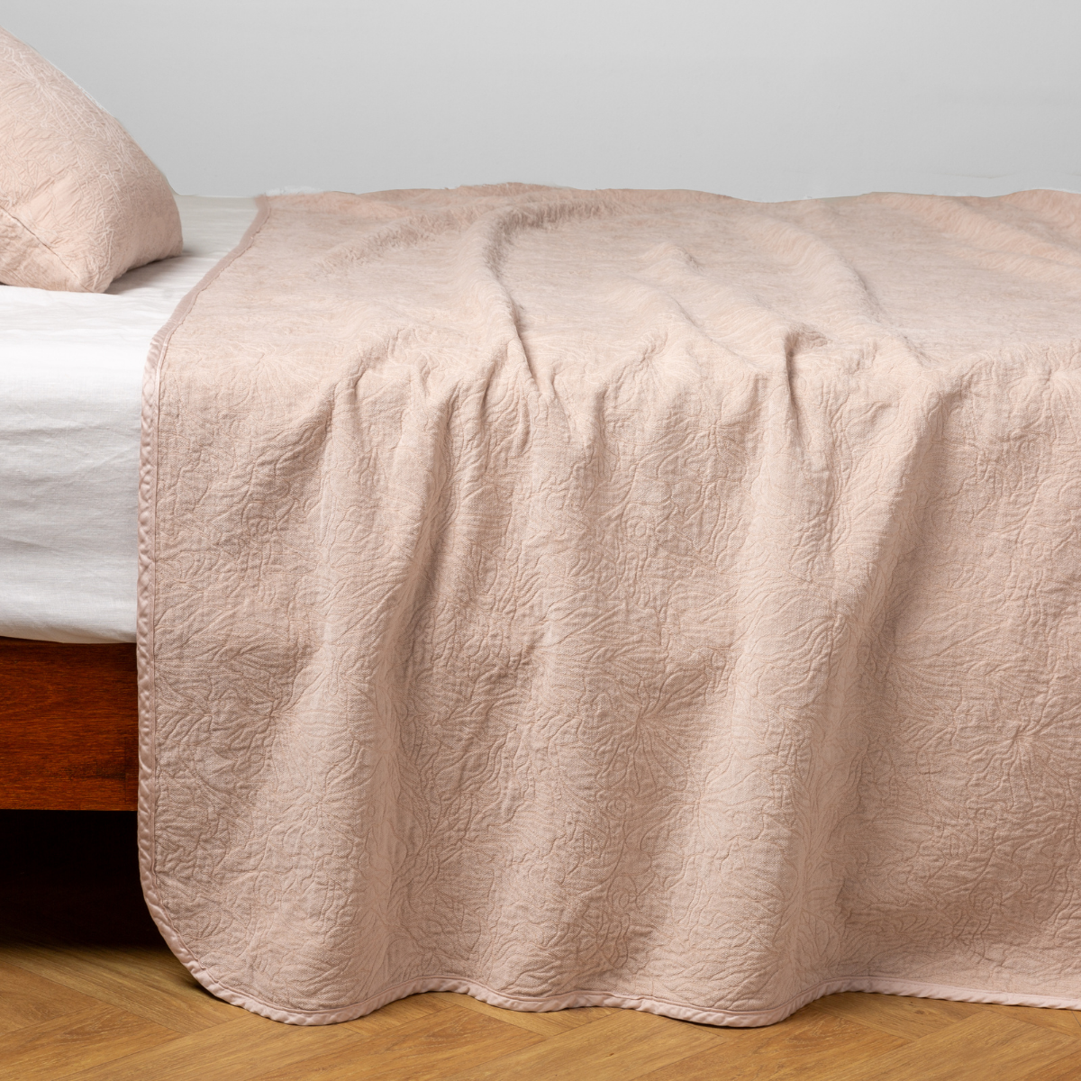 Pearl: side view of the chenille jacquard side of a bedspread with the cotton jacquard side showing on the matching sham β shown with a winter white fitted sheet.