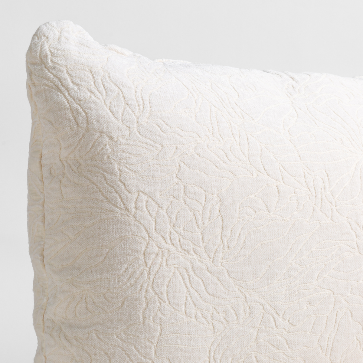 Winter White: close up of the chenille jacquard corner of a pillow cushion with a single-line floral pattern.