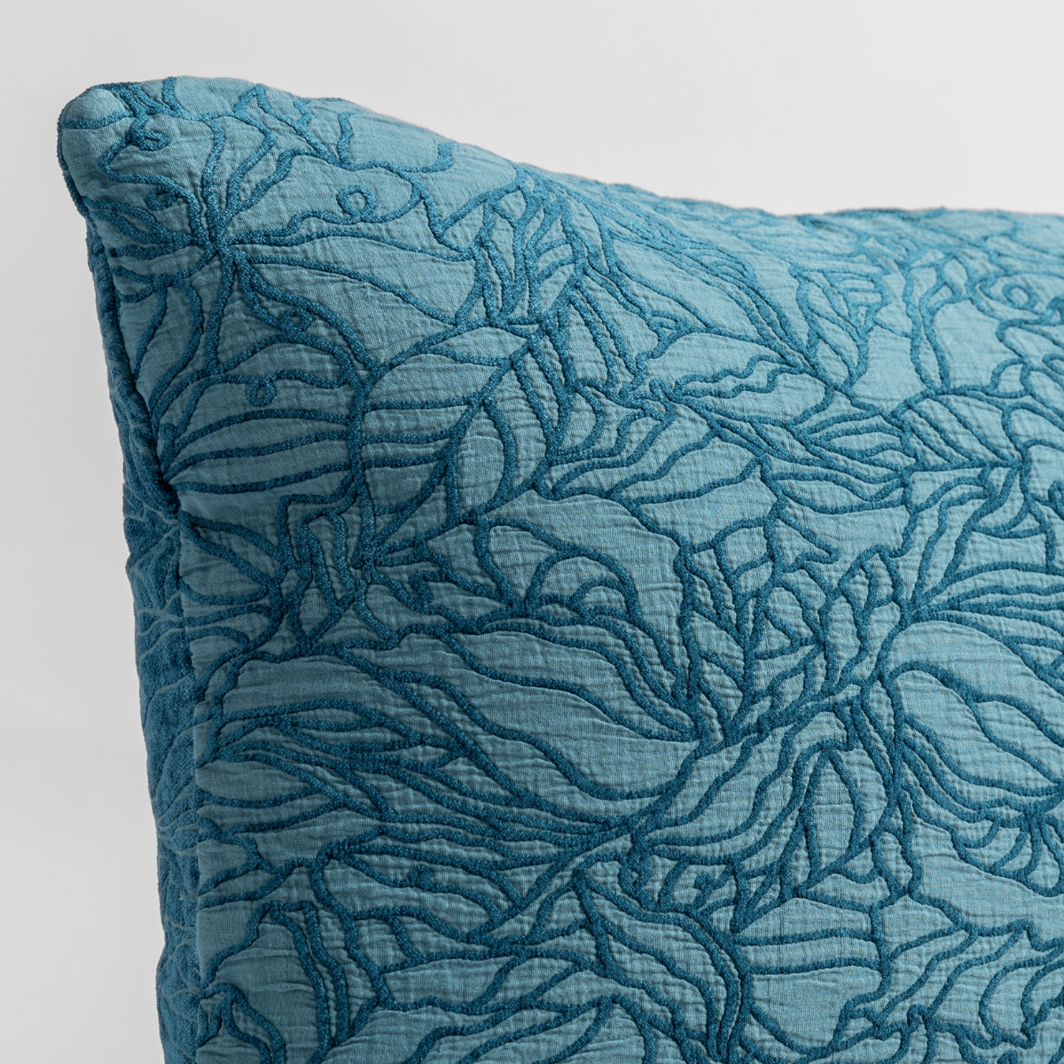 Cenote: close up of the cotton jacquard corner of a pillow cushion with a single-line floral pattern.
